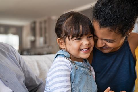 A child sits with their parent or guardian and laughs.