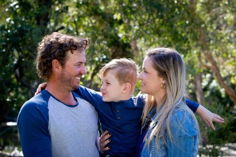 Two parents hold their child and smile at one another